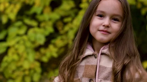 Static close up of girl smiling and forming heart hands in green forest Stock Footage 346622419
