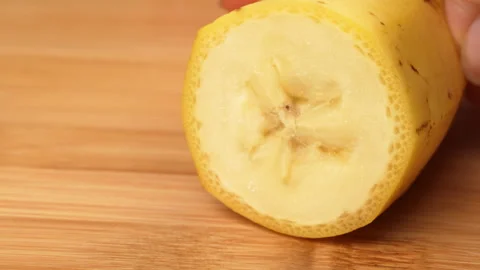 Static Close Up Hand Cutting Unpeeled Yellow Banana On Board 4K Stock Footage 322140306