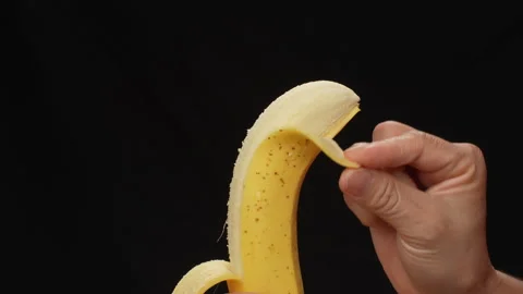 Static Close Up Hand Peeling Ripe Yellow Banana On Black Background 4K Stock Footage 322142045