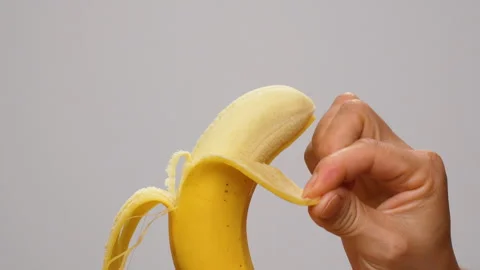 Static Close Up Hand Peeling Ripe Yellow Banana On White Background 4K Stock Footage 322142203