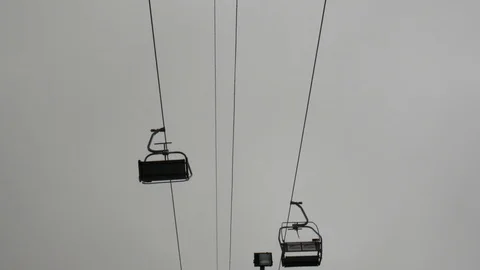 Static close up shot of chairlifts functioning with people, snowy background Stock Footage 121309179