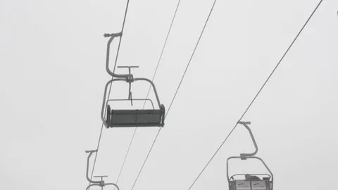 Static close up shot of chairlifts functioning with people, snowy background Stock Footage 121352858