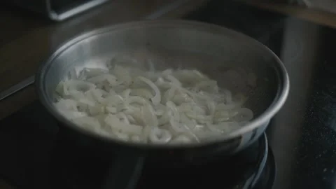 Static close up shot of chopped onions sauteing and simmering in frying pan Stock Footage 342242015