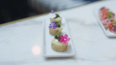 Static close-up shot of elegant bite-sized appetizers arranged on a white Vidéo 333675890