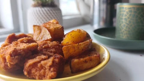 Static close-up shot of a hand adding golden seasoned potato wedges onto a Vídeos de archivo 334785519