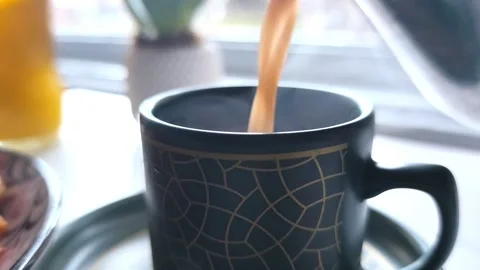 Static close-up shot of hot coffee being poured from a silver pitcher into a Vídeos de archivo 334700099