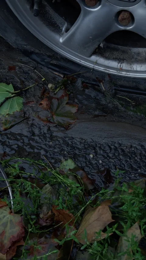 Static close-up of vehicle wheel rim and tire pressed into wet mud beside Stock Footage 344968255