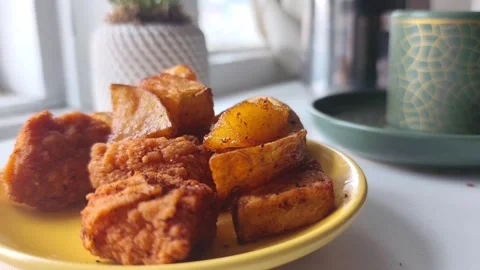 Static close-up view of a hand taking a crispy fried chicken piece from a yellow Vídeos de archivo 334785580