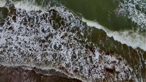 Static drone shot of the ocean with calm waves reaching the shore of a white Stock Footage 284444123