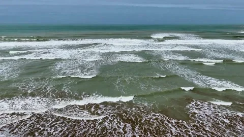 Static drone shot of the ocean with calm waves reaching the shore of a white Stock Footage 284444226