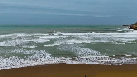 Static drone shot of the ocean with calm waves reaching the shore of a white Stock Footage 284444434