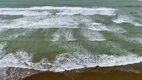Static drone shot of the ocean with calm waves reaching the shore of a white Stock Footage 284444484