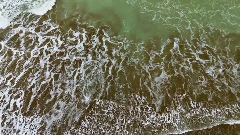Static drone shot of the ocean with calm waves reaching the shore of a white Stock Footage 284446227