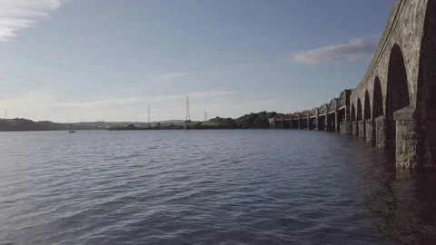 Static Drone Shot of Railway Bridge Over River Tamar with Distant Pylons 4k Stock Footage 320946579