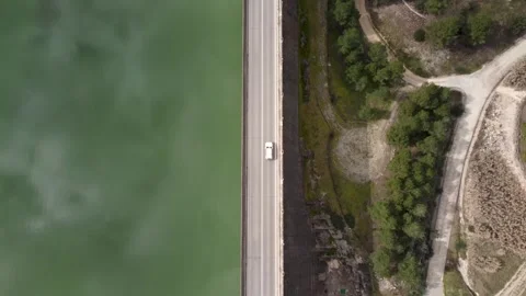 Static drone view from above of a road divides a reservoir and a wooded area Stock Footage 255849676