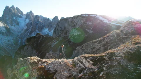 Static drone view captures male hiker crossing rocky alpine terrain near Tre Stock Footage 346768933