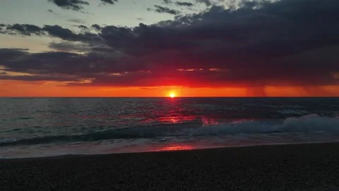 Static drone view of ocean waves rolling onto a pebble beach during sunset. The Vidéo 336720036