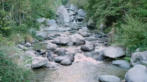 Static FHD shot of a clear mountain stream flowing around large rocks and 库存影片 334165750