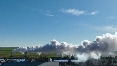 Static footage of a factory with two chimneys emitting dense white smoke Stock Footage 312994876