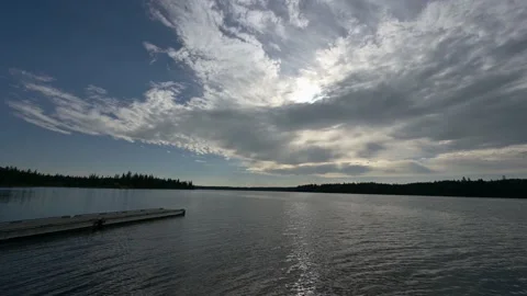Static footage of a large lake with a dock on the left side and a large cloud Stock Footage 220083069