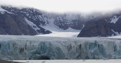 Static Glacier Flowing out of Mountains into Bay Stock Footage 54302517