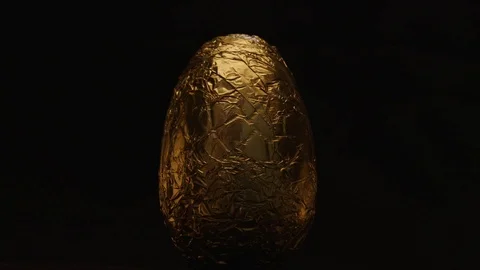 Static golden wrapped Easter egg on black cove with warm cinematic light Stock Footage 127366901