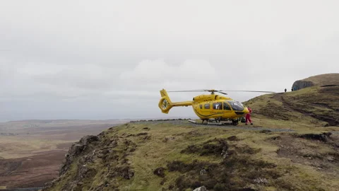 Static ground shot of a yellow NHS rescue helicopter landed in the Scottish Stock Footage 335125302