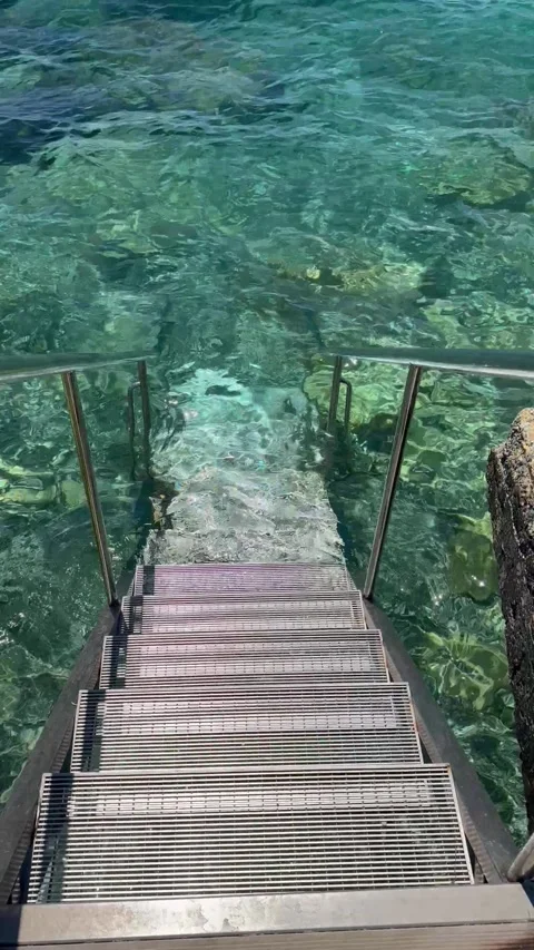 Static high angle shot of metal stairs leading into crystal clear turquoise sea Stock Footage 337366717