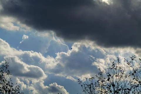 Static image of dark helicopter flying over head with blue cloudy sky in the Stock Photos