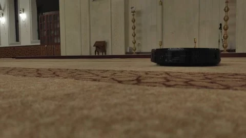 Static low-angle shot of a black robotic vacuum cleaner operating on a patterned Vídeos de archivo 334108364