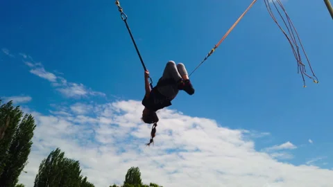 Static Low Angle Shot of Child Performing Acrobat Flip on Outdoor Bungee Stock Footage 335921791
