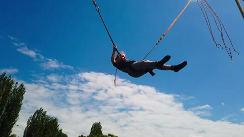 Static Low Angle Shot of Child Jumping on Outdoor Bungee Trampoline against Stock Footage 336121607