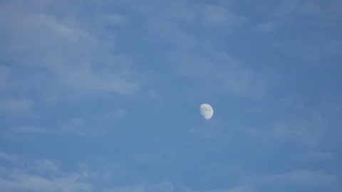 Static low angle view of daytime moon in blue sky with thin clouds Video stock 337201881