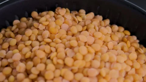 Static macro showcase of dry orange lentils in black bowl 4k Stockbeeldmateriaal 340440787