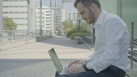 Static medium shot of Caucasian man with laptop sitting on bench Stock Footage 97923444