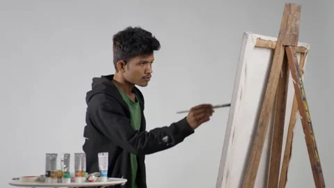 A static mid shot of a man painting on a canvas board Stock Footage 280501227