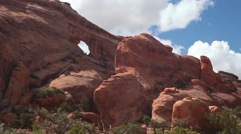 Static MS small arch in Arches National Park, blue sky, white clouds, with trees Stock Footage 41750537