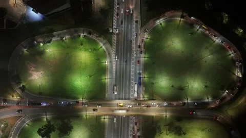 Static overhead night aerial of road junction with floodlit lawns and traffic Vídeo Stock 342648480
