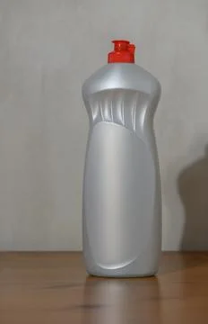 Static plastic bottle with white and red accents on wooden surface in neutr.. Photos