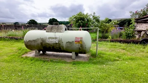 Static propane gas tank stands on concrete supports in a rural English yard Stock Footage 339209721