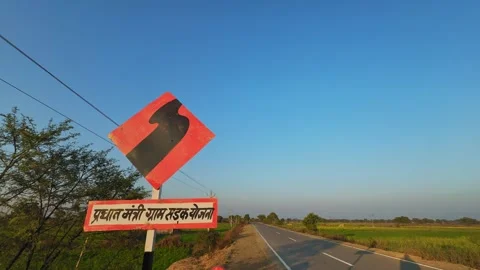 Static roadside shot of a curve warning sign with Hindi text referencing Stock Footage 328572067