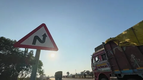 Static roadside shot of triangular winding road warning sign as a covered cargo Stock Footage 327390470