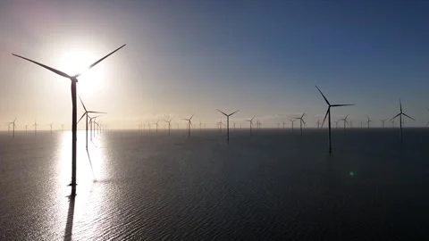 Static row of offshore turbines with flickering sunrise light Stock Footage 331826831