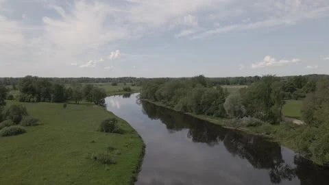 Static scene of a calm river flowing through meadows and forests in summer day Stock Footage 159982498