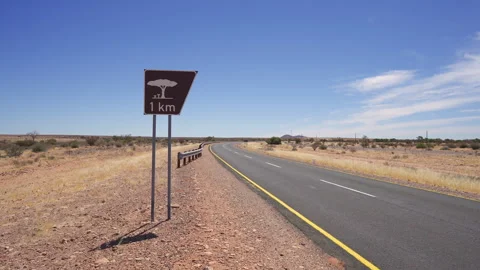 Static shot of a 1 Km roadside sign beside an empty desert highway in Namibia 스톡 동영상 347917610