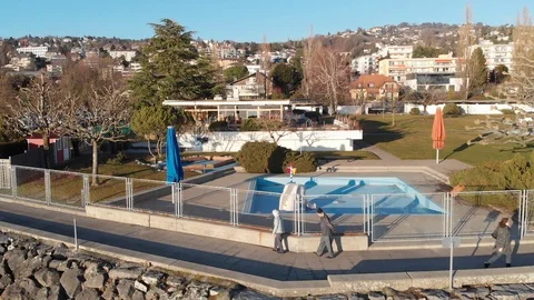Static shot of 3 people walking by the shore in a Swiss town. Stock Footage 125707417