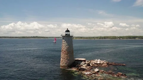 Static shot of an abandoned New England lighthouse with a sailboat nearby-aerial Stock Footage 161264059