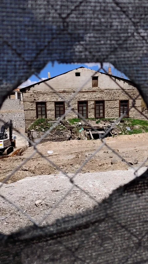 Static shot of an ancient stone house viewed through a hole in a wire fence. Vídeos de archivo 333908410