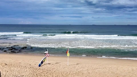 Static Shot of Bar Beach with Surf Flags and Surfers in Newcastle, Australia Stock Footage 313873603
