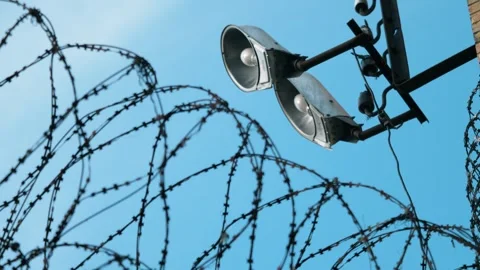 Static shot of the barbed wire with a focus pull to the security lamps. 스톡 동영상 303568450